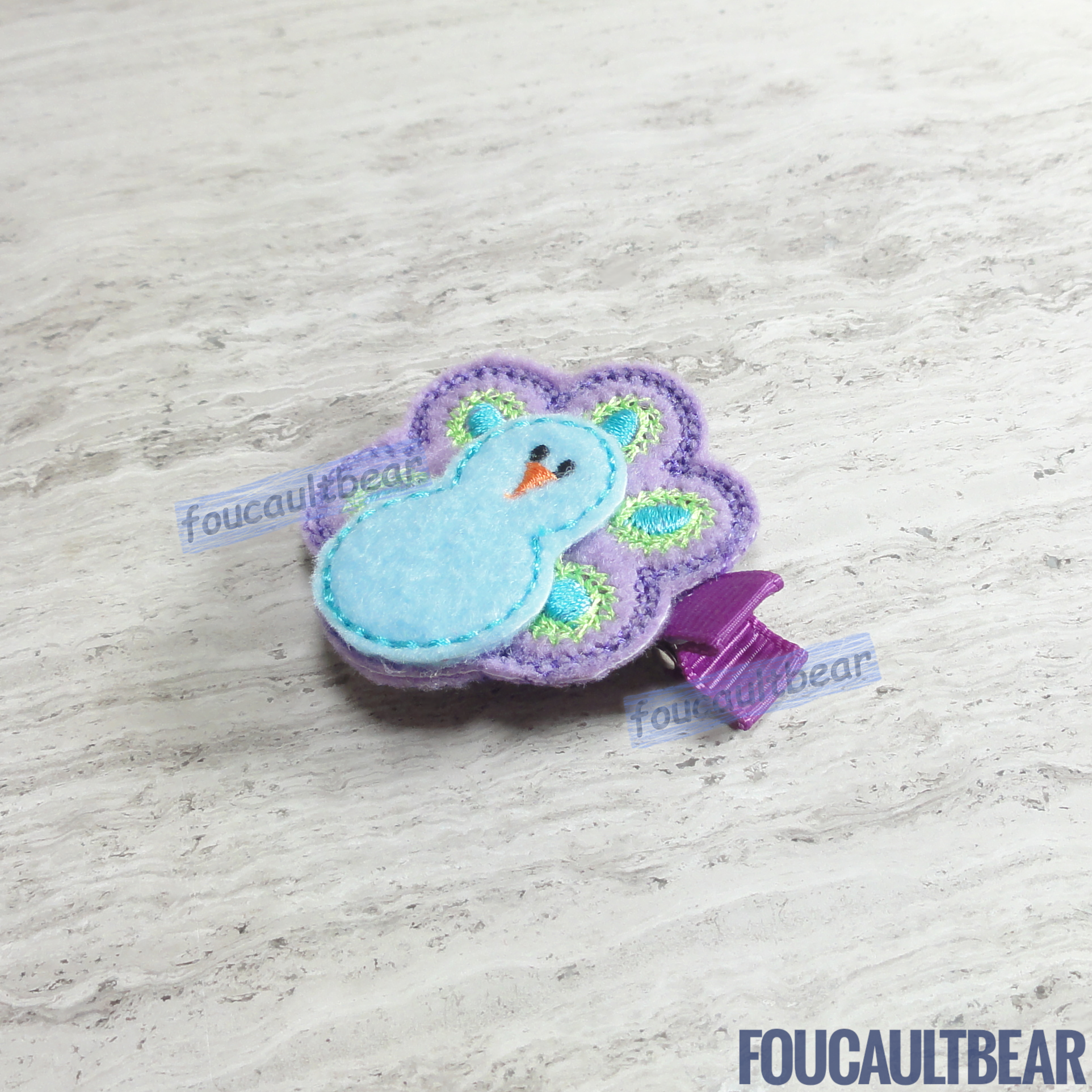 Foucaultbear's. HANDMADE HAIR CLIPPIE. Pastel Purple Peacock. Embroidered Soft Felt. Partially Lined Alligator Hair Clip. Cute Pastel Peacock Hair Clippie. A great addition to your little girl's wardrobe. Perfect for toddlers, preschoolers, elementary-schoolers. Absolutely adorable on babies with enough hair to wear it too. Makes for a great baby Shower gift. Definitely not your standard cliché shower gift. Why not be the first to introduce variety to the baby's otherwise boring wardrobe? 