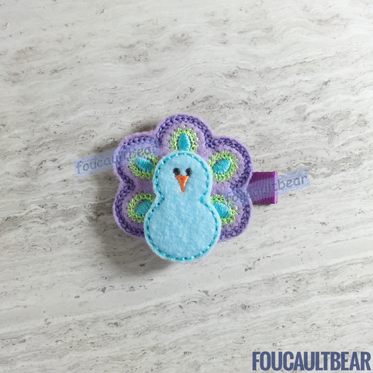 Foucaultbear's. HANDMADE HAIR CLIPPIE. Pastel Purple Peacock. Embroidered Soft Felt. Partially Lined Alligator Hair Clip. Cute Pastel Peacock Hair Clippie. A great addition to your little girl's wardrobe. Perfect for toddlers, preschoolers, elementary-schoolers. Absolutely adorable on babies with enough hair to wear it too. Makes for a great baby Shower gift. Definitely not your standard cliché shower gift. Why not be the first to introduce variety to the baby's otherwise boring wardrobe? 
